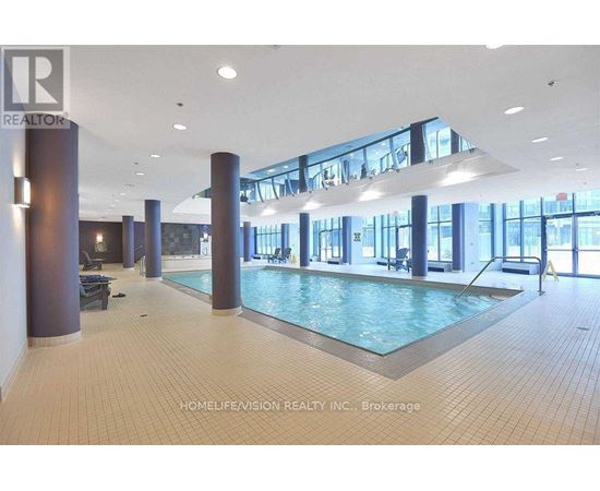 A large indoor swimming pool with a tiled floor and a glass wall.
