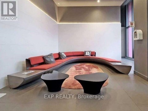 A modern living room with a red couch and black ottoman.