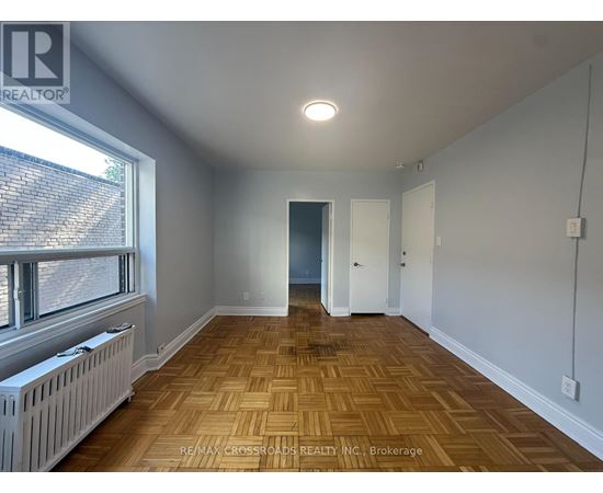 A room with wooden flooring and a window with blinds.