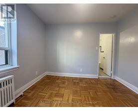 A room with wooden flooring and a door leading to another room.