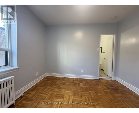 A room with wooden flooring and a door leading to another room.