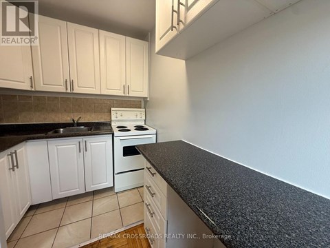 A kitchen with white cabinets and a black countertop.