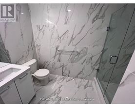 A bathroom with marble tiles and a glass shower stall.