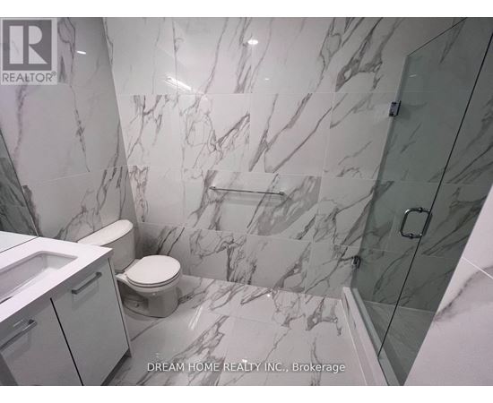 A bathroom with marble tiles and a glass shower stall.