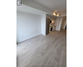 A spacious room with a kitchen area in the background.