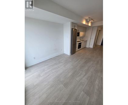 A spacious room with a kitchen area in the background.