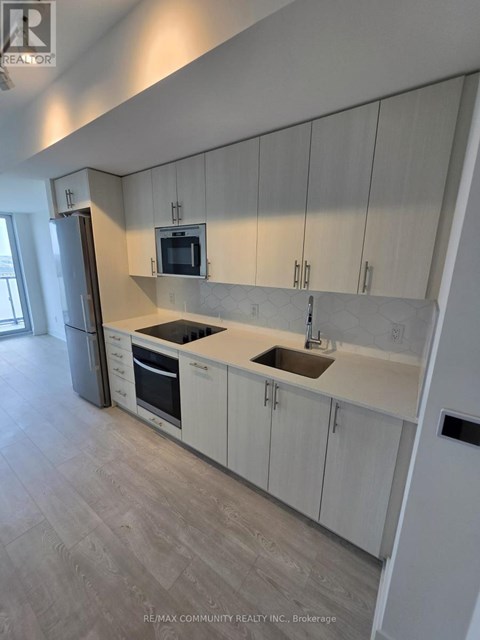 A kitchen with white cabinets and a grey floor.