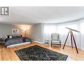 A bedroom with a bed, chair, and rug.