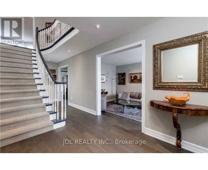 A spacious hallway with a staircase, a mirror, and a wooden table.