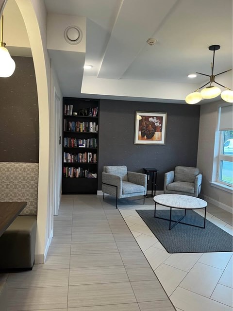 A living room with a grey couch, a grey armchair, a coffee table and a bookshelf.