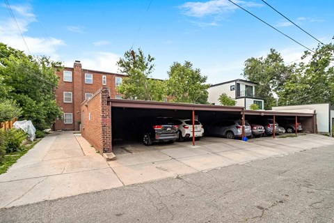 A parking garage with cars parked inside and a building to the left.