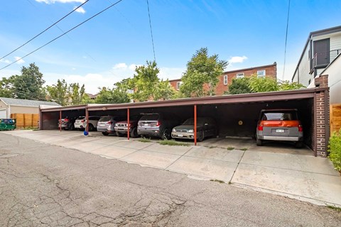 A parking garage with cars parked inside and a building in the background.