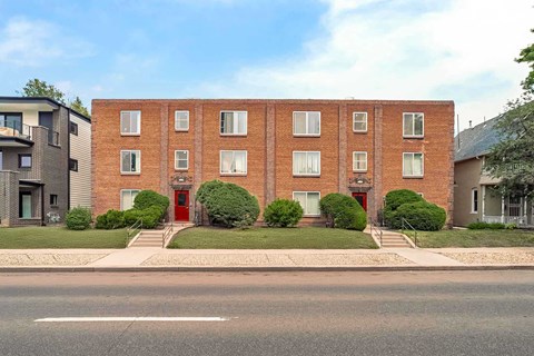 A red brick building with a red door in front.