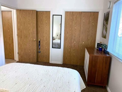 A bedroom with a bed, wardrobe, and a mirror.