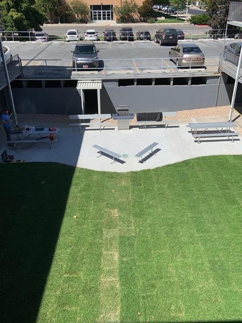 A parking lot with cars and a green grassy area.