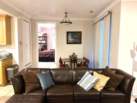 A living room with a brown leather couch and a painting on the wall.