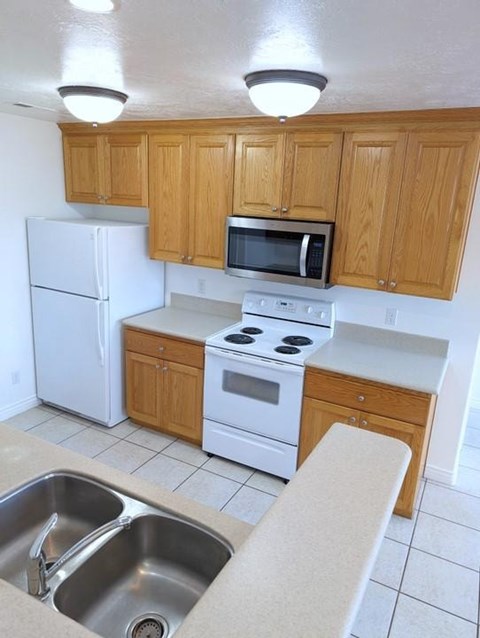 A kitchen with white appliances and wooden cabinets.