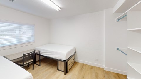 A bedroom with a bed, chair, and shelves.