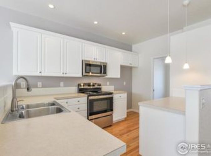A kitchen with white cabinets and a stainless steel sink.