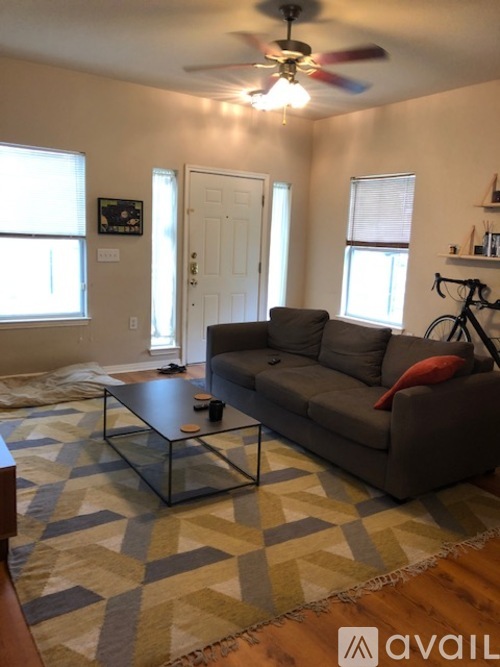 A living room with a couch, coffee table, and a fan.