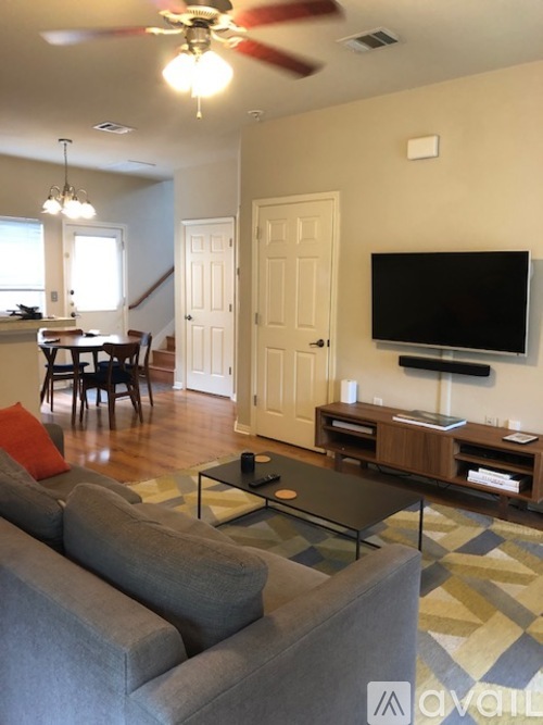 A living room with a grey couch and a television on the wall.
