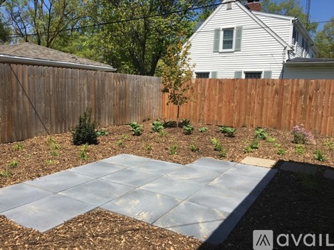 A backyard with a wooden fence and a grey stone patio.
