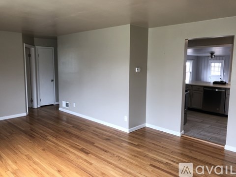A room with wooden floors and a white wall with a door and a window.