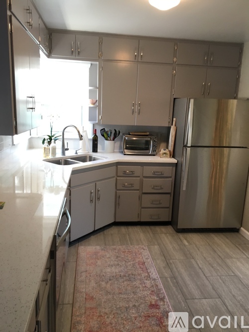 A kitchen with a sink, refrigerator, and cabinets.