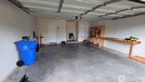 A spacious garage with a blue dumpster and a workbench.