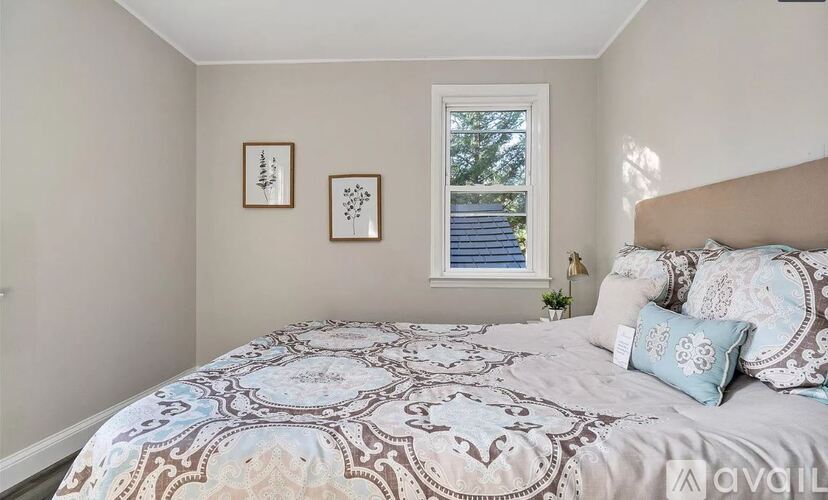A bedroom with a large bed and two pictures on the wall.