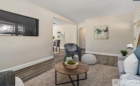 A living room with a grey couch, a coffee table, and a painting on the wall.