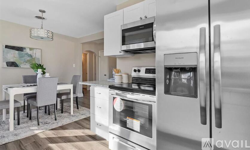 A modern kitchen with stainless steel appliances and a dining table set for four.