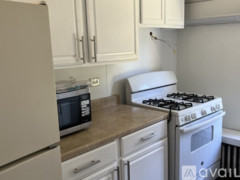 A kitchen with a white gas stove and a microwave on the counter.