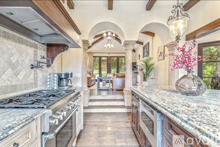 A kitchen with a marble countertop and a black stove top.
