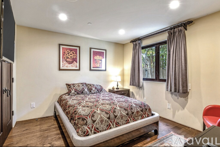 A bedroom with a large bed and two pictures on the wall.