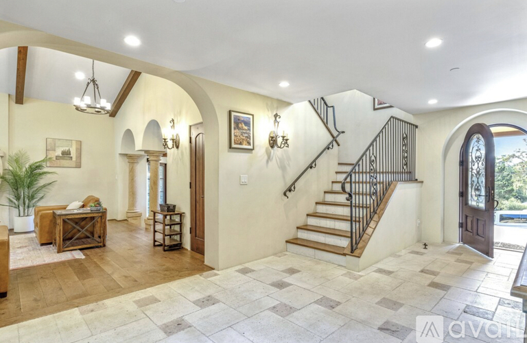 A spacious foyer with a staircase and a rug.