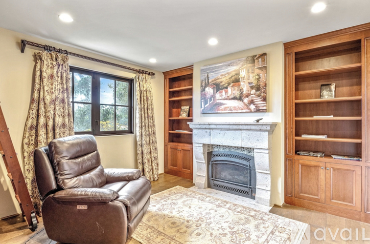 A living room with a fireplace, a chair, and a painting on the wall.