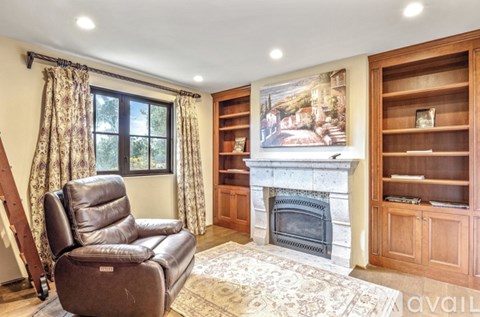 A living room with a fireplace, a chair, and a painting on the wall.