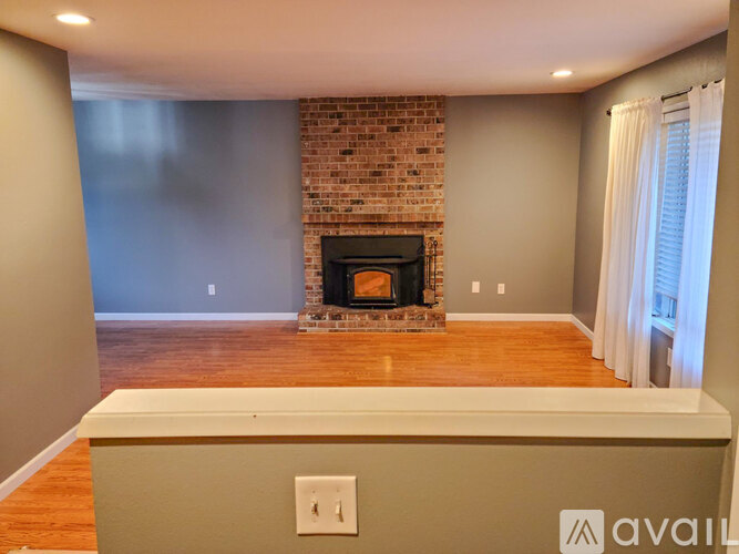 A living room with a fireplace and wooden floors.