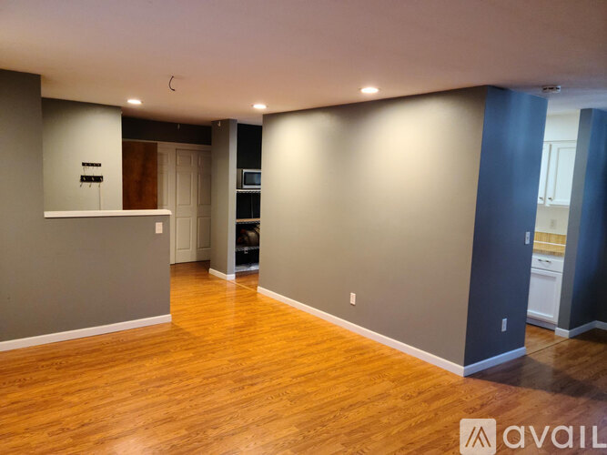 A spacious room with wooden flooring and a white ceiling.