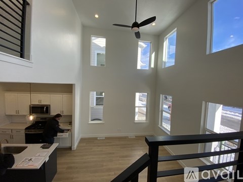 A person is standing in a kitchen with a fan on the ceiling.