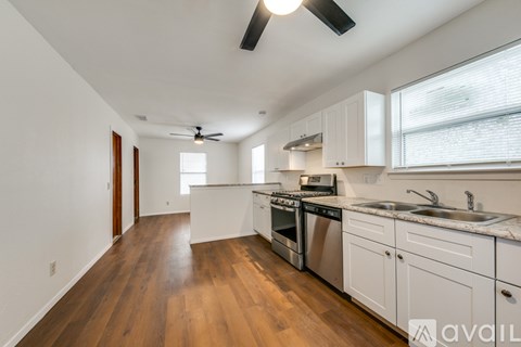 A kitchen with white cabinets and a wooden floor.