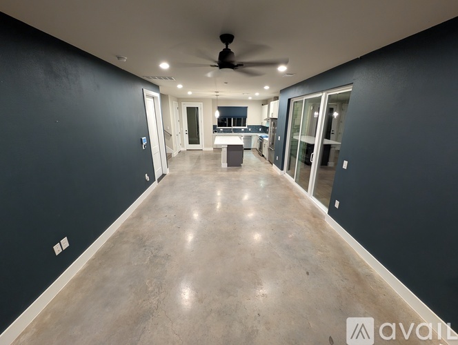 A spacious room with a ceiling fan and a kitchen area in the background.