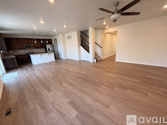 A spacious room with wooden floors and a ceiling fan.