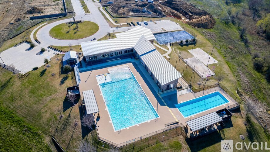 An aerial view of a swimming pool and a building with a metal roof.