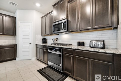 A kitchen with dark brown cabinets and a white door.