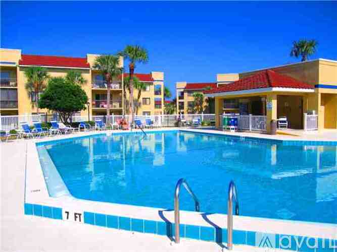 A large swimming pool in front of a building with a red roof.