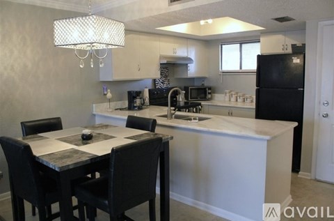 A kitchen with a table and chairs in the foreground and a refrigerator in the background.