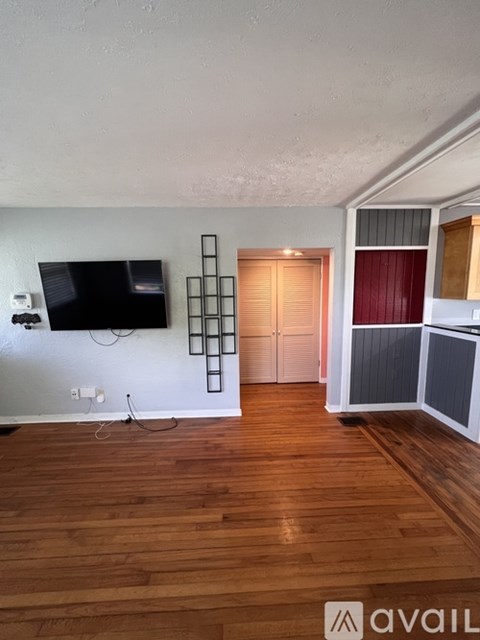 A room with a wooden floor and a flat screen TV mounted on the wall.