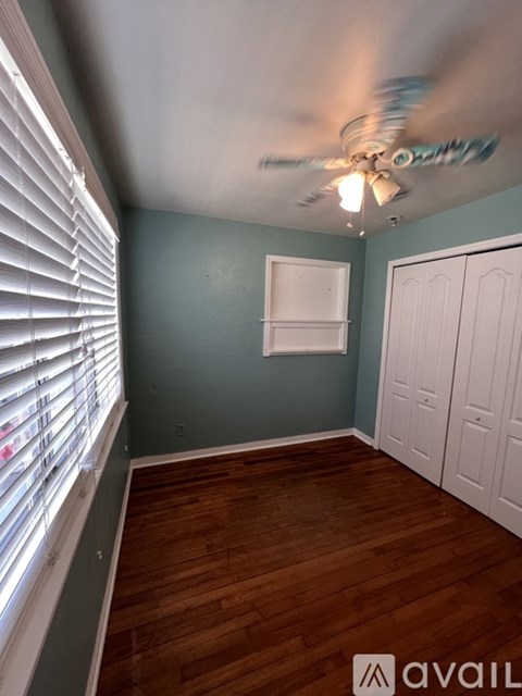 A room with a ceiling fan and wooden flooring.